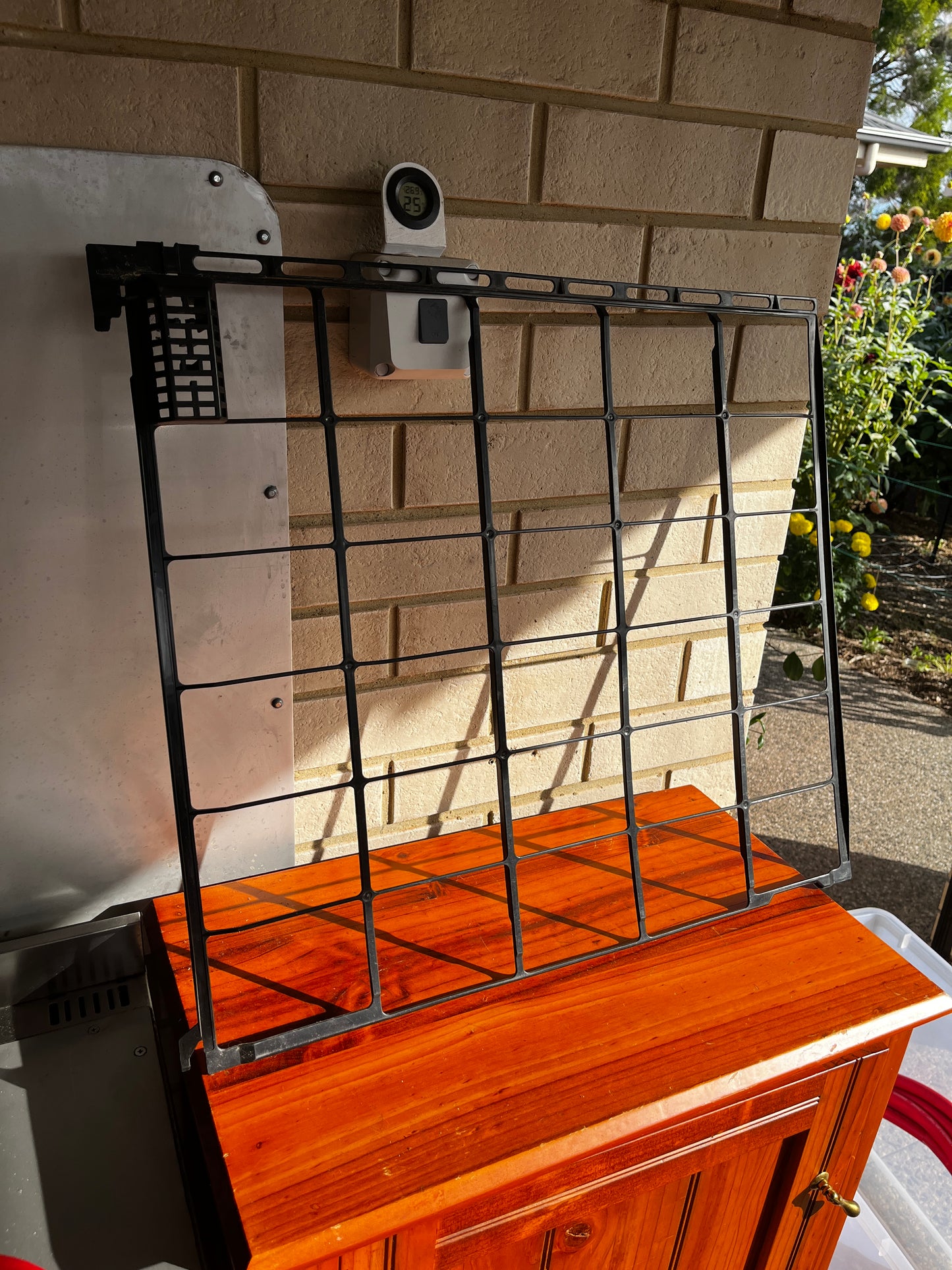 Black plastic grill grate leaning on a wooden surface outdoors