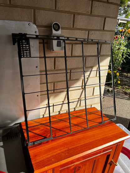 Black plastic grill grate leaning on a wooden surface outdoors