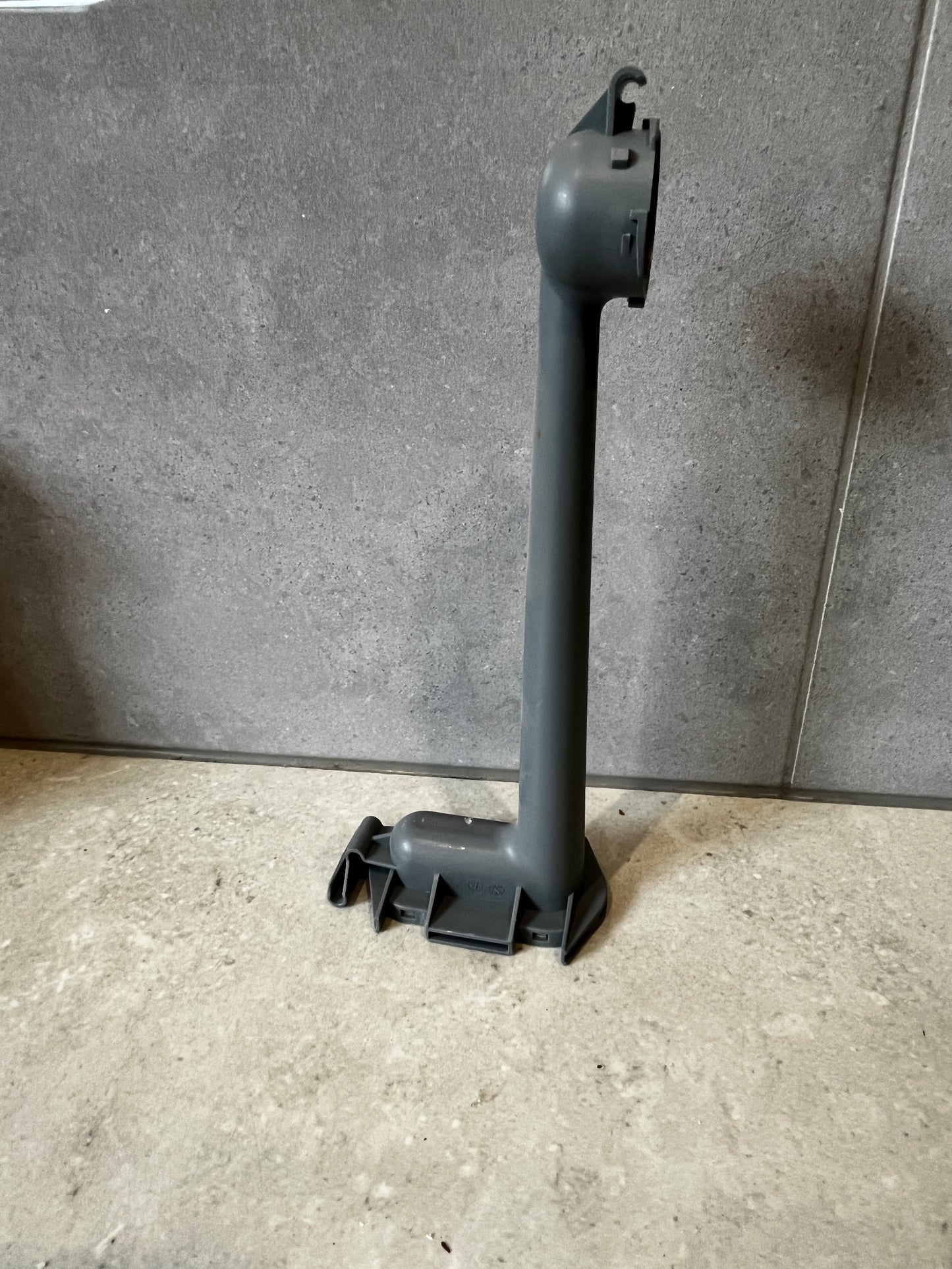 Dishwasher lower spray arm support standing upright on a tiled surface
