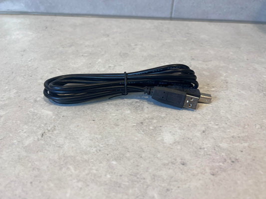 Coiled black USB A to USB B cable displayed on a light surface