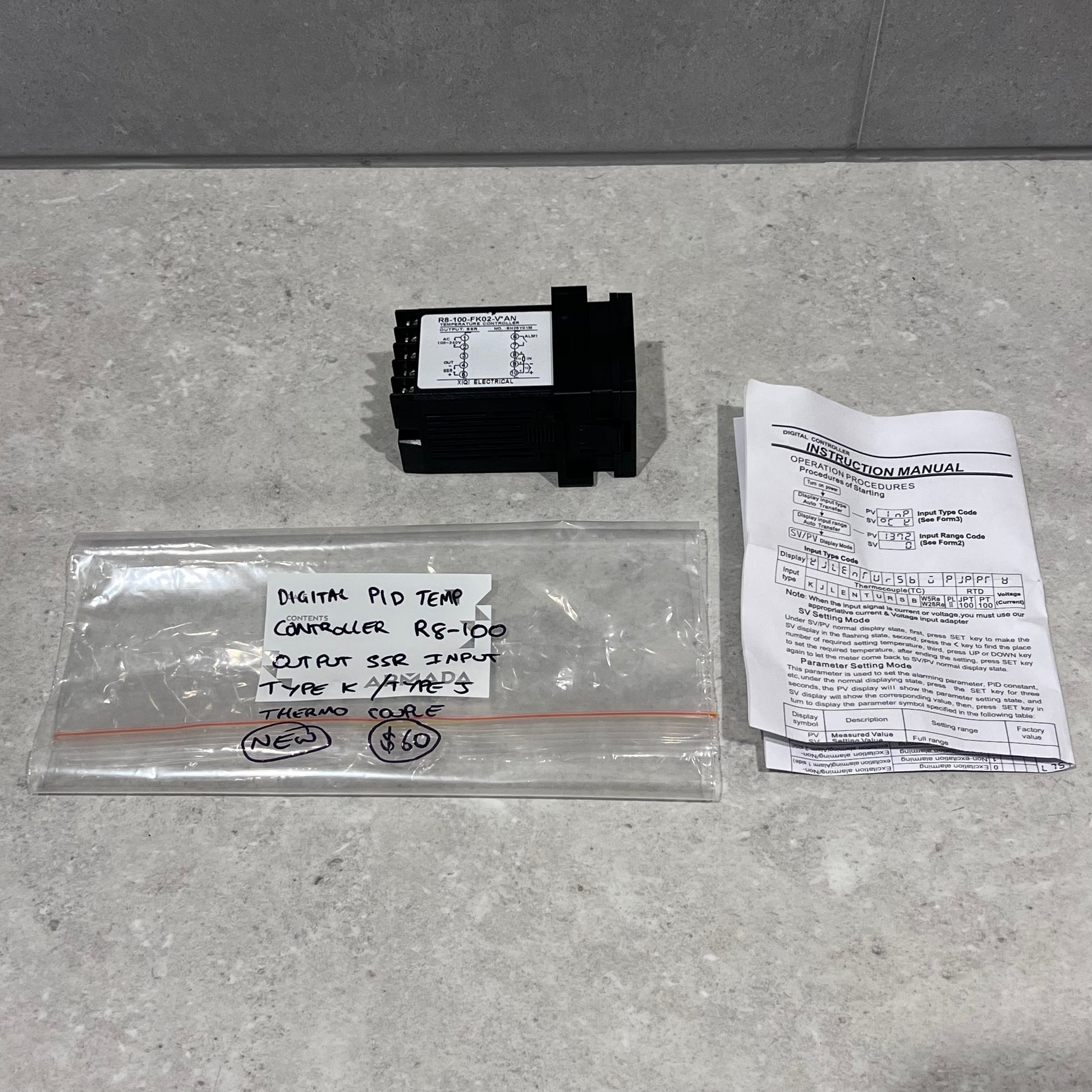 SHYB R8-100 Digital PID Temperature Controller with instruction manual and labeled storage bag on a countertop