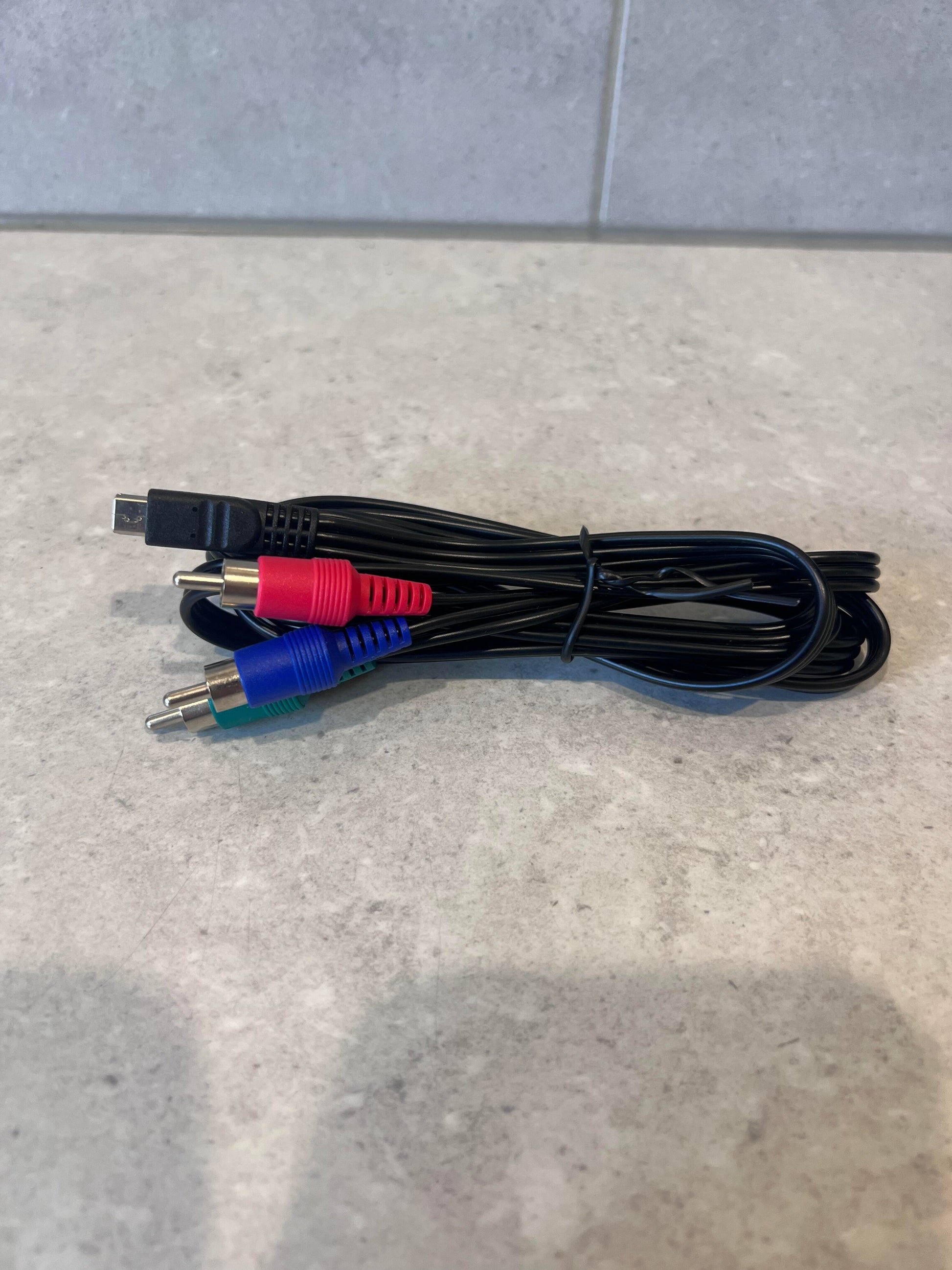 Coiled AV RCA to mini USB cable with red, green, and blue connectors on a stone surface