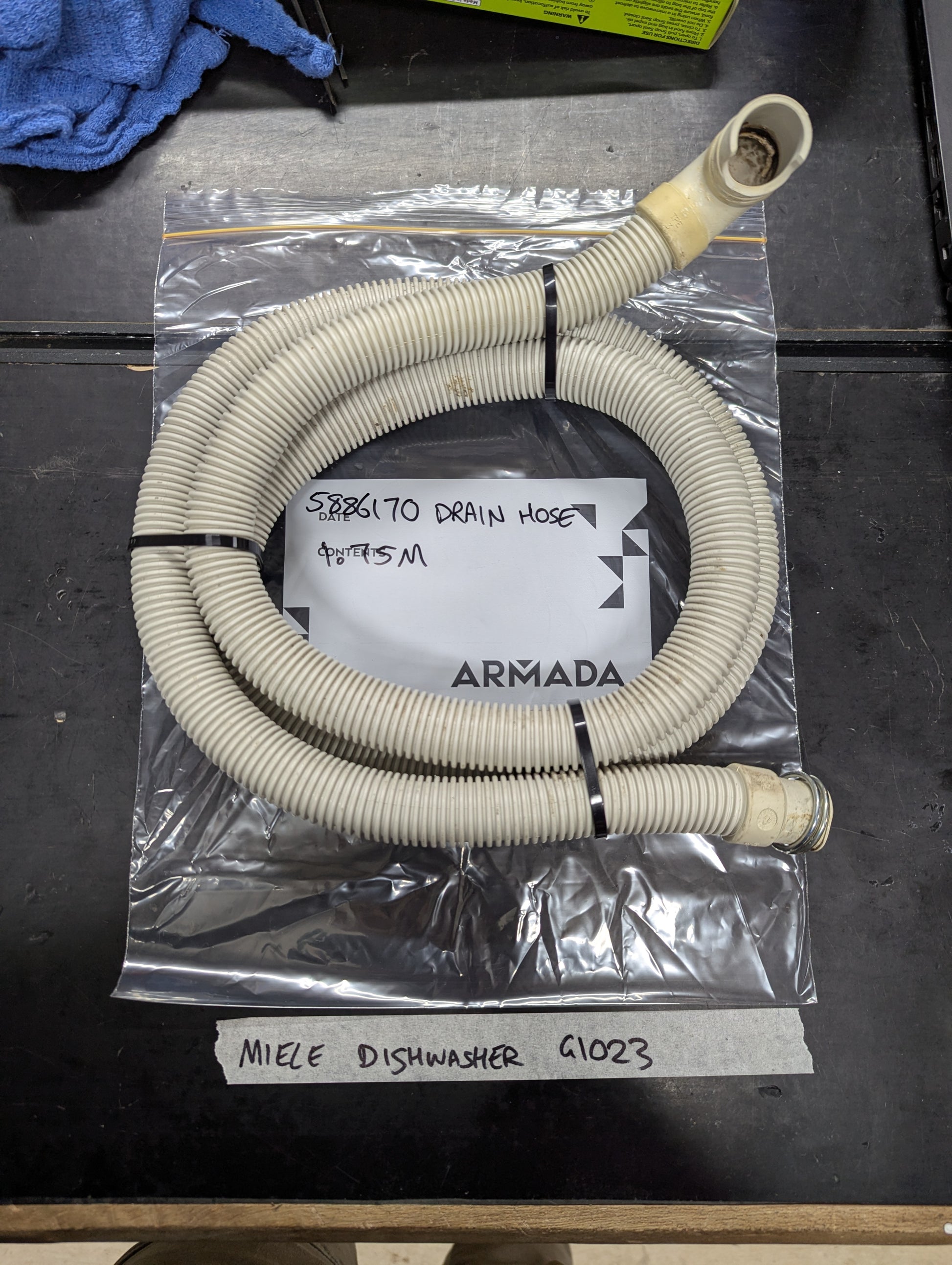 Miele G1023 dishwasher drain hose coiled on table with connectors visible