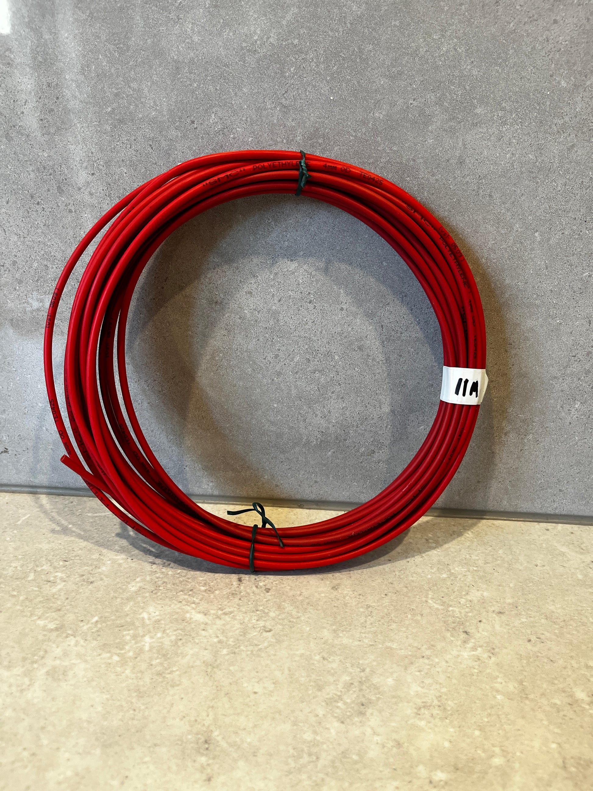 Coil of red polyethylene tubing on a light surface