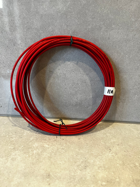 Coil of red polyethylene tubing on a light surface