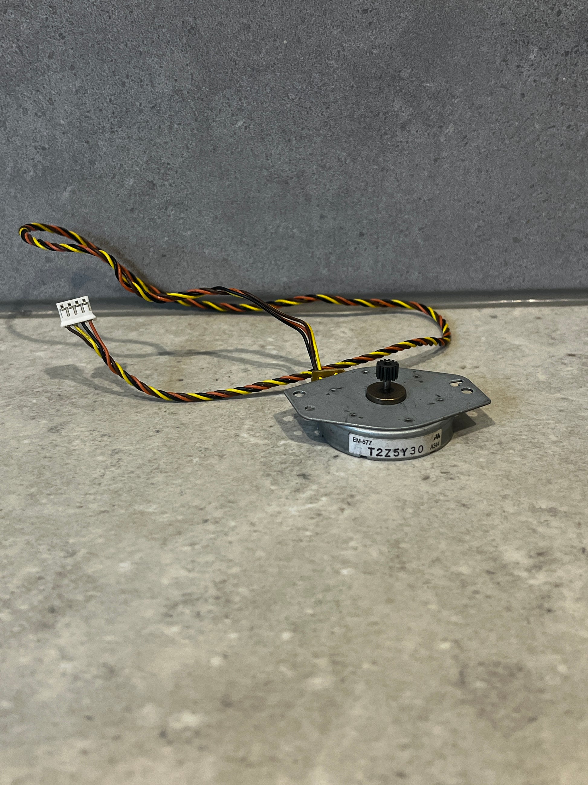 Compact metal stepper motor with twisted multi-color wiring and gear on shaft