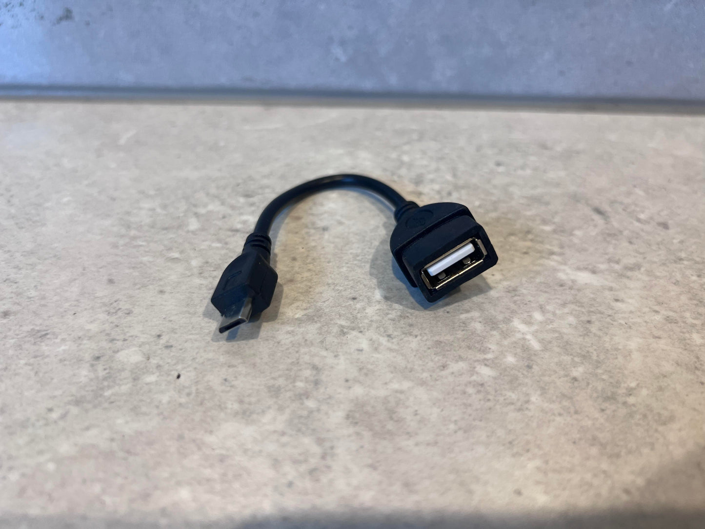 Micro USB to USB OTG adapter cable on a countertop