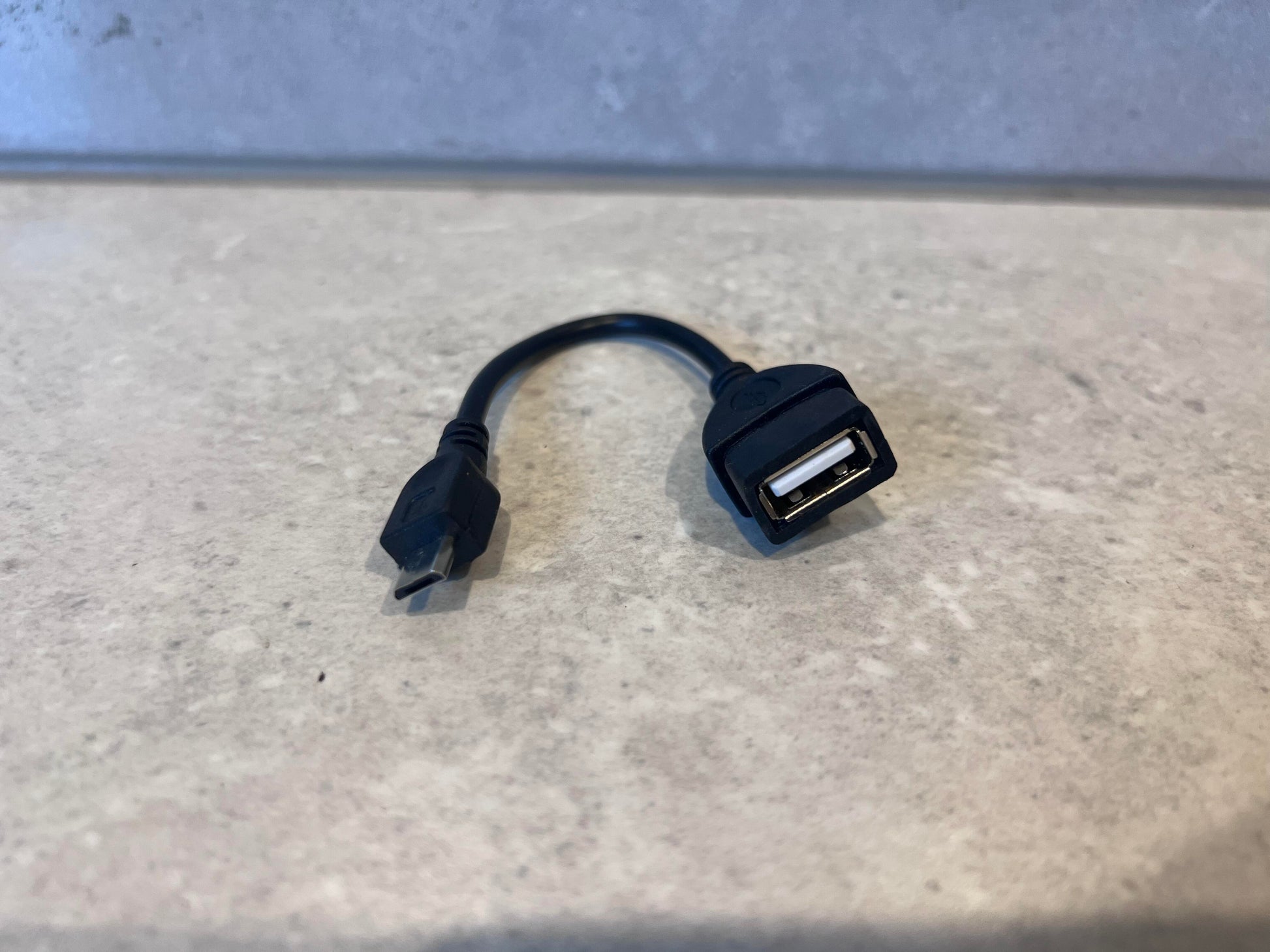 Micro USB to USB OTG adapter cable on a countertop