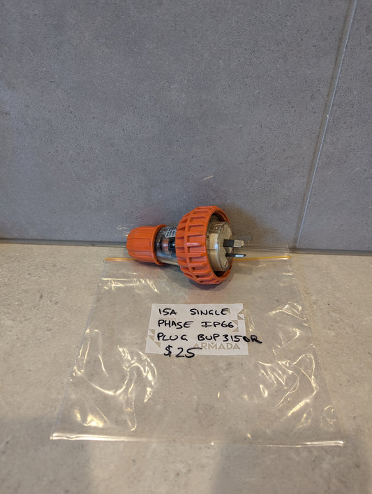 15A Single Phase IP66 electrical plug with orange locking collar and visible prongs, displayed on a counter next to labeled bag