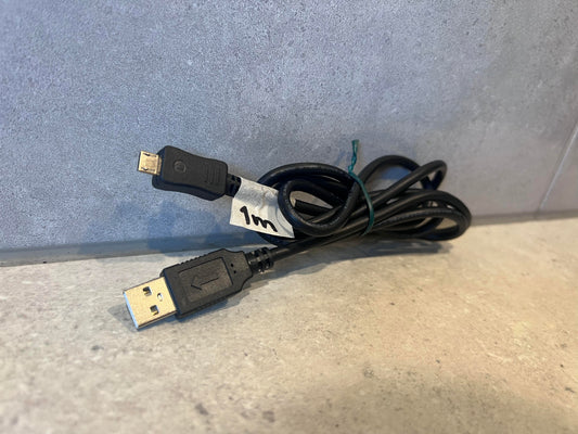 Coiled black USB to Micro USB charging cable with 1m label on stone background