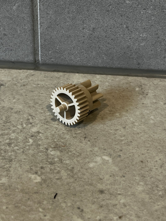 Beige plastic spur gear component on stone surface