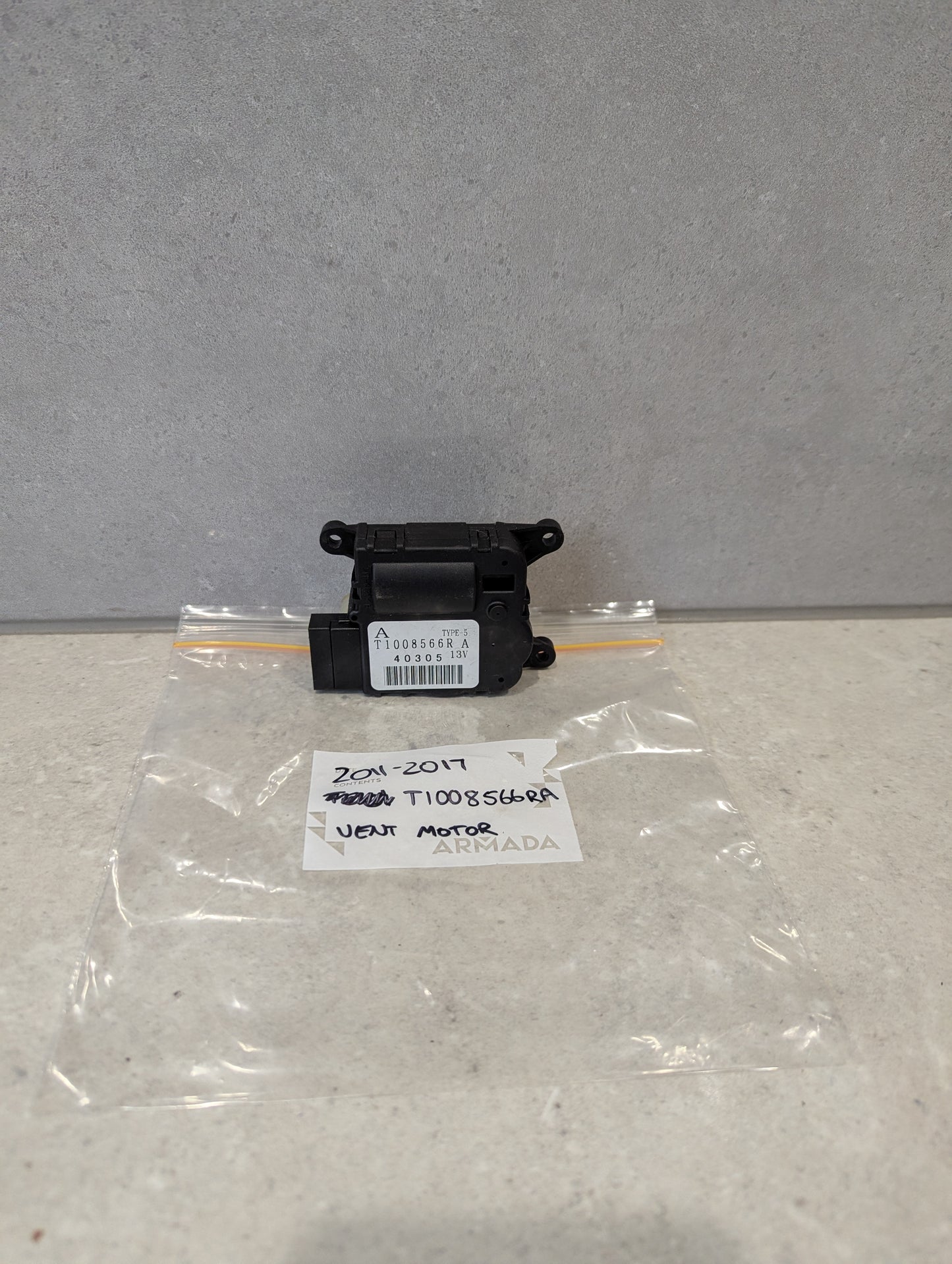Front close-up of Nissan heater vent flap control actuator part T1008566RA with connector and mounting holes  