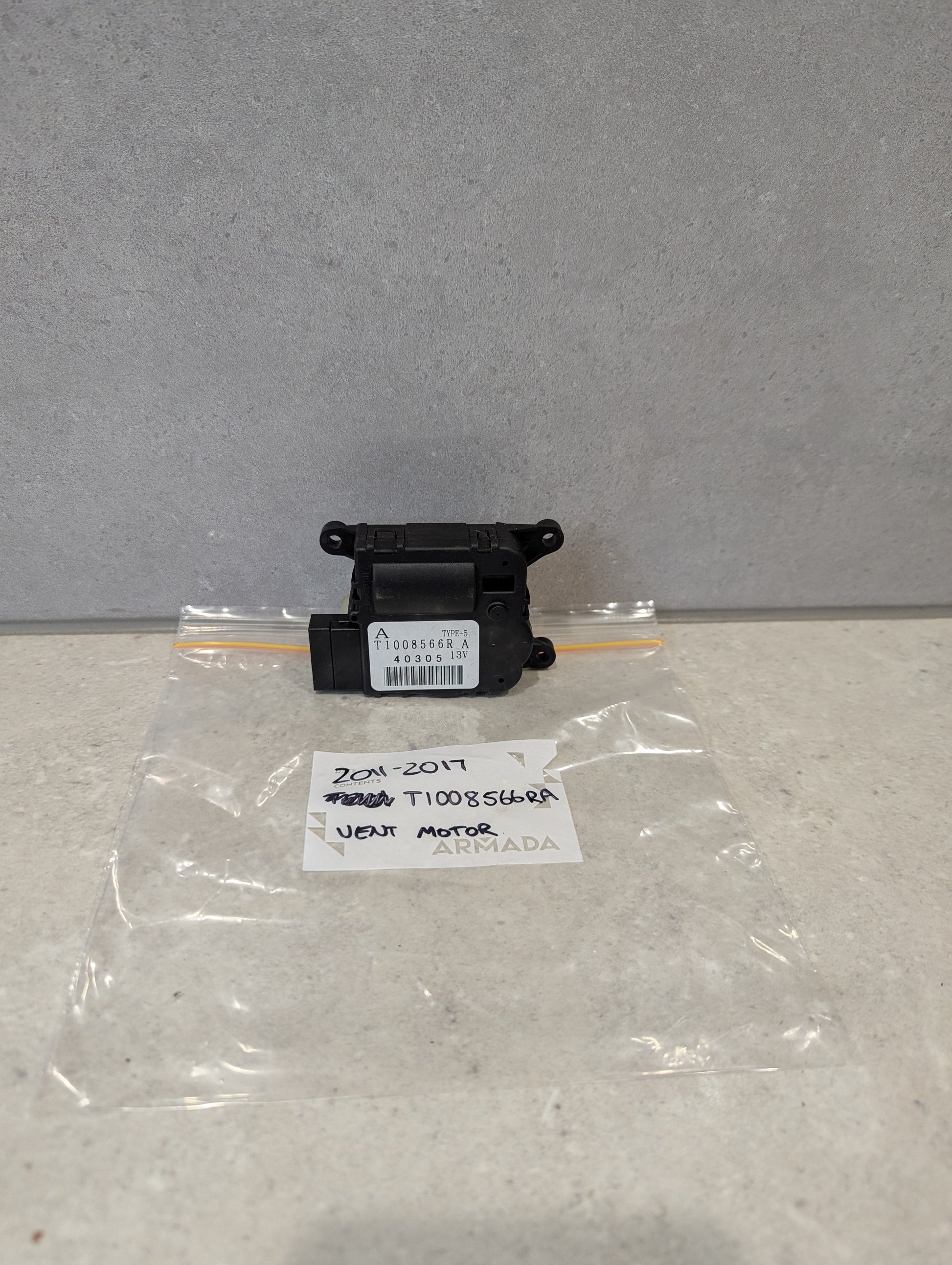Front close-up of Nissan heater vent flap control actuator part T1008566RA with connector and mounting holes  