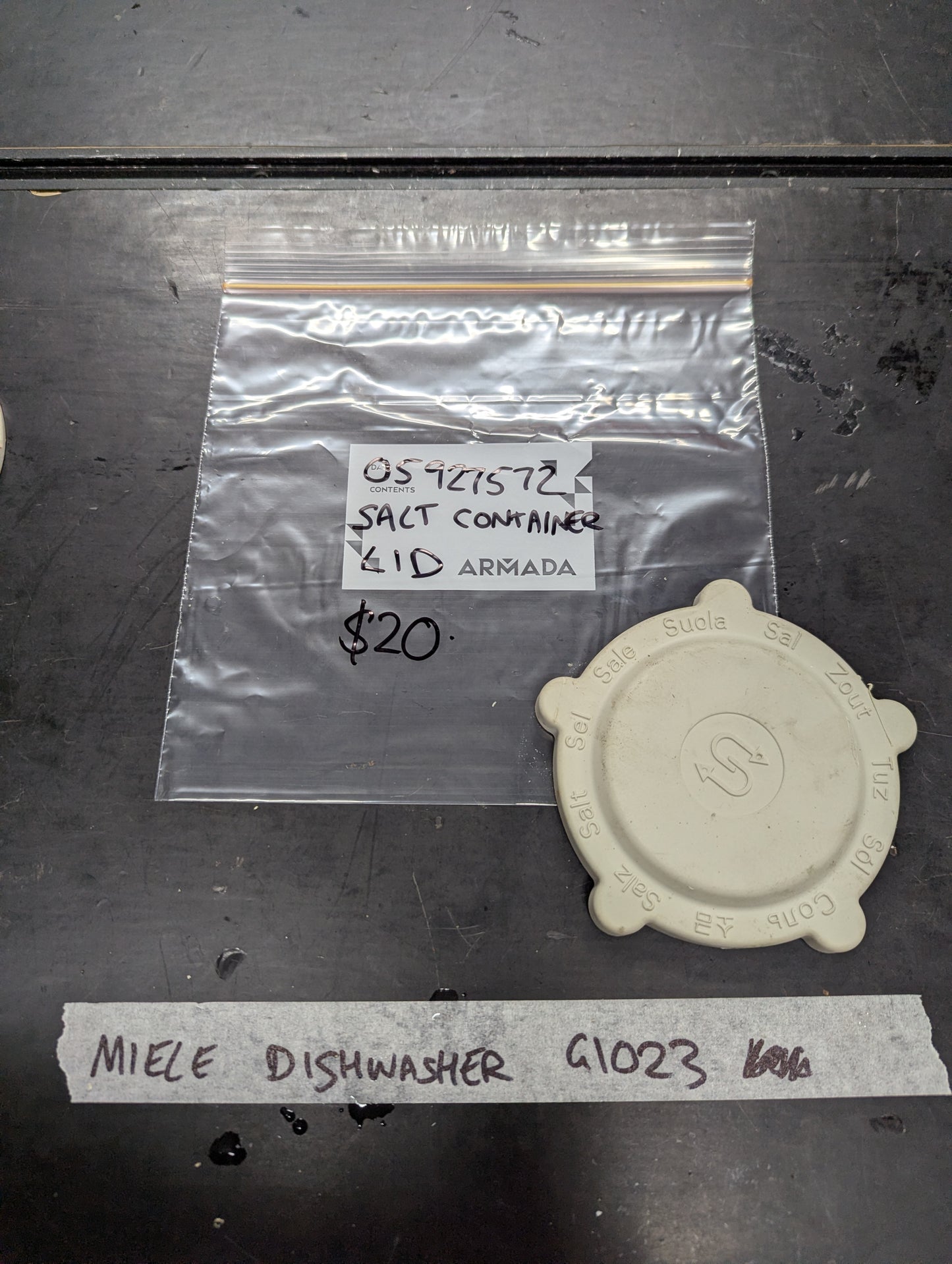 White plastic salt container lid for Miele dishwasher G1023 displayed next to labeled bag