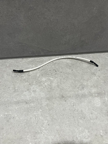 White insulated electrical wire with black-taped ends lying on a gray surface