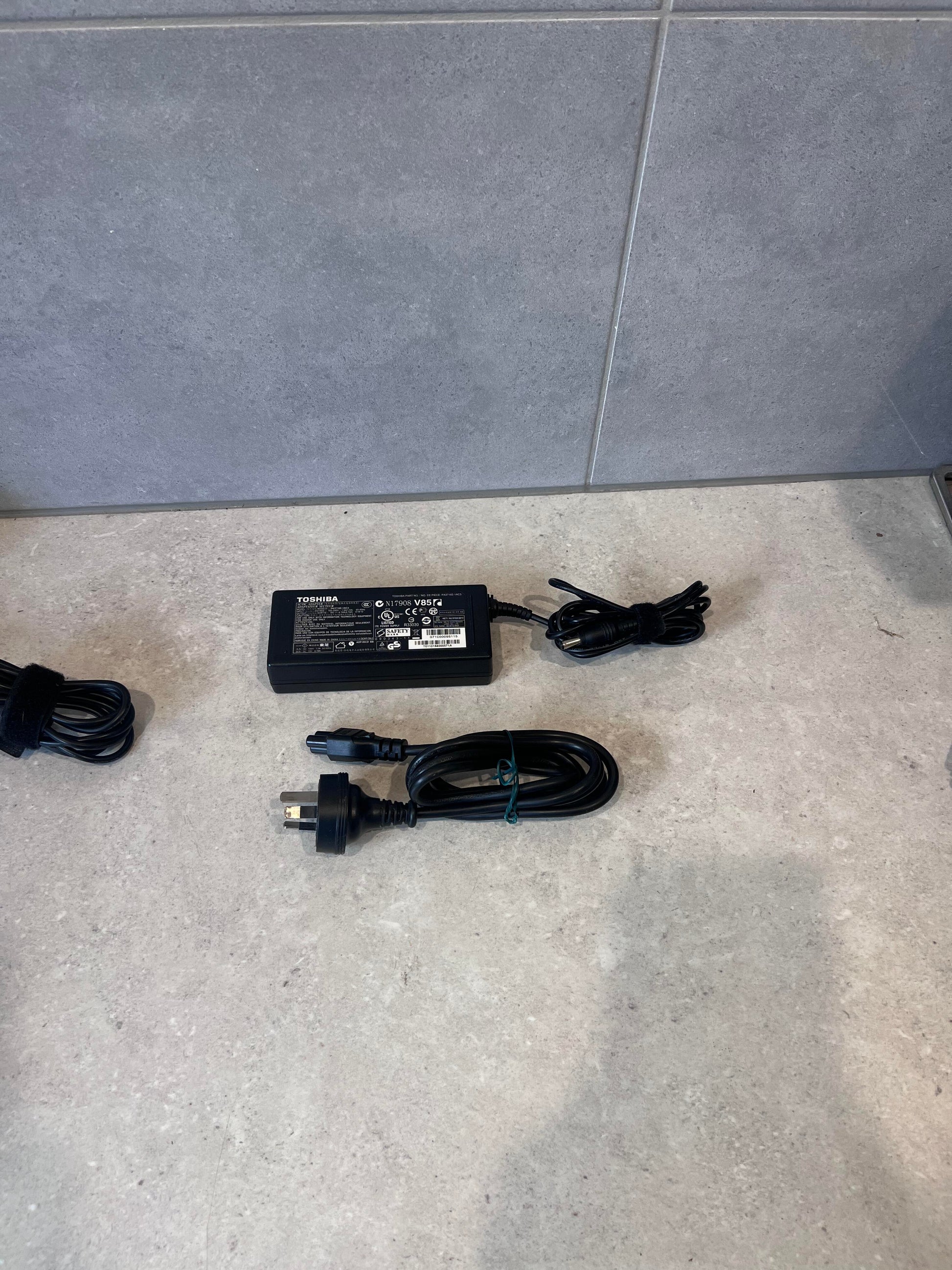 Toshiba AC/DC laptop power adapter with cords on a countertop