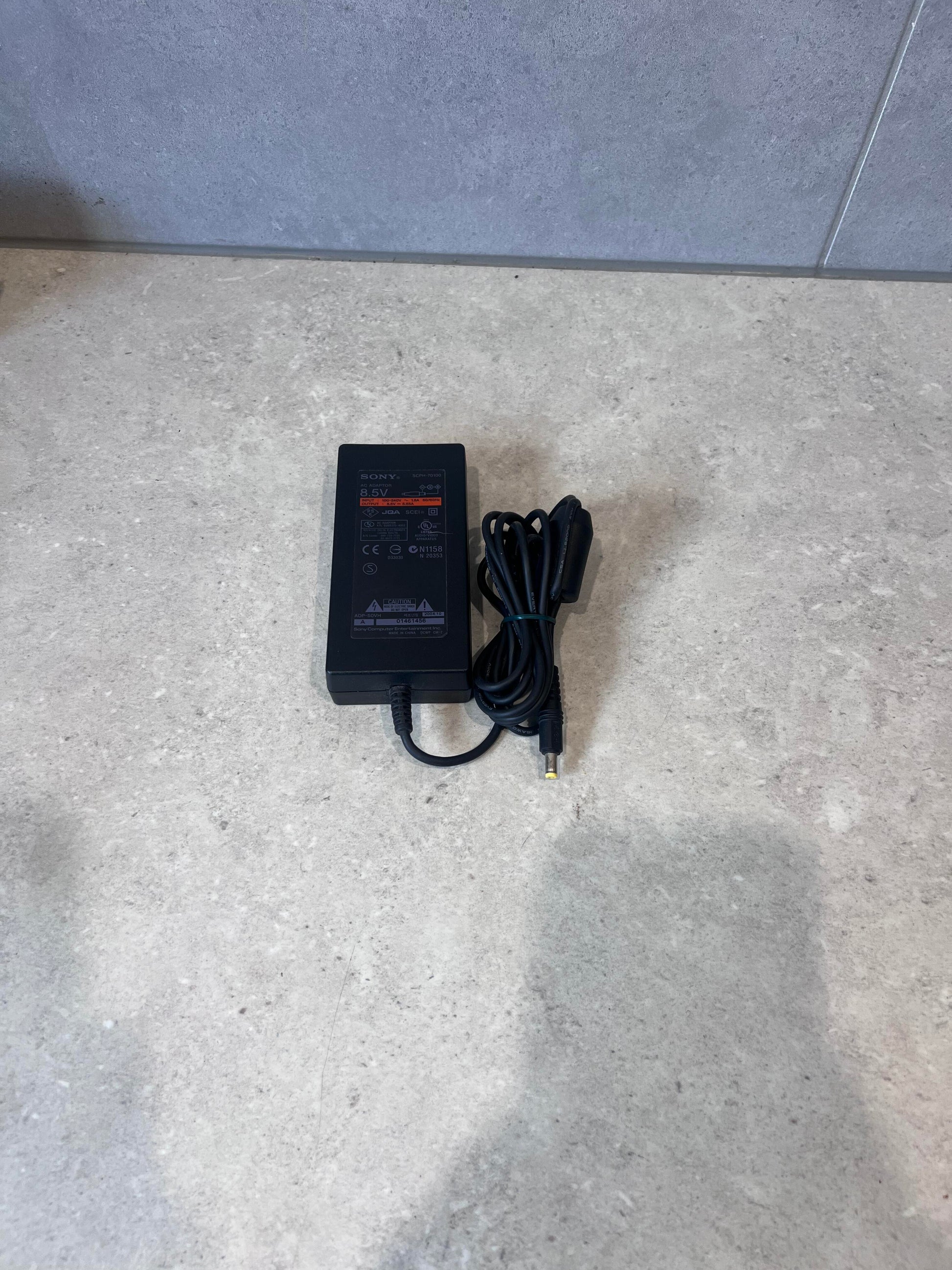 Sony 8.5V AC power adapter with attached cable on a gray surface