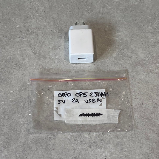 Oppo 5V 2A USB-A wall charger and labeled plastic bag on gray surface
