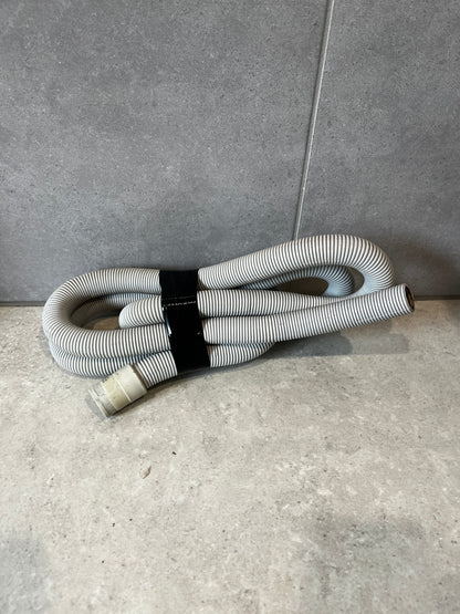 Flexible corrugated plastic drain hose coiled on a tiled floor