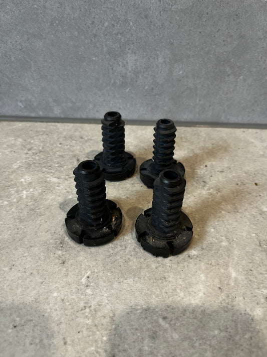 Set of four black plastic replacement leveling feet on a gray surface