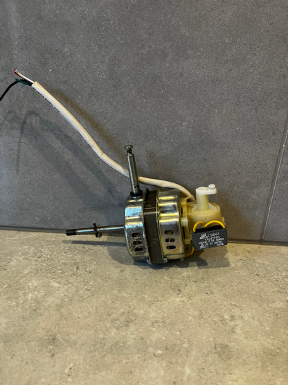 Electric motor with capacitor and attached white wires laying on grey surface