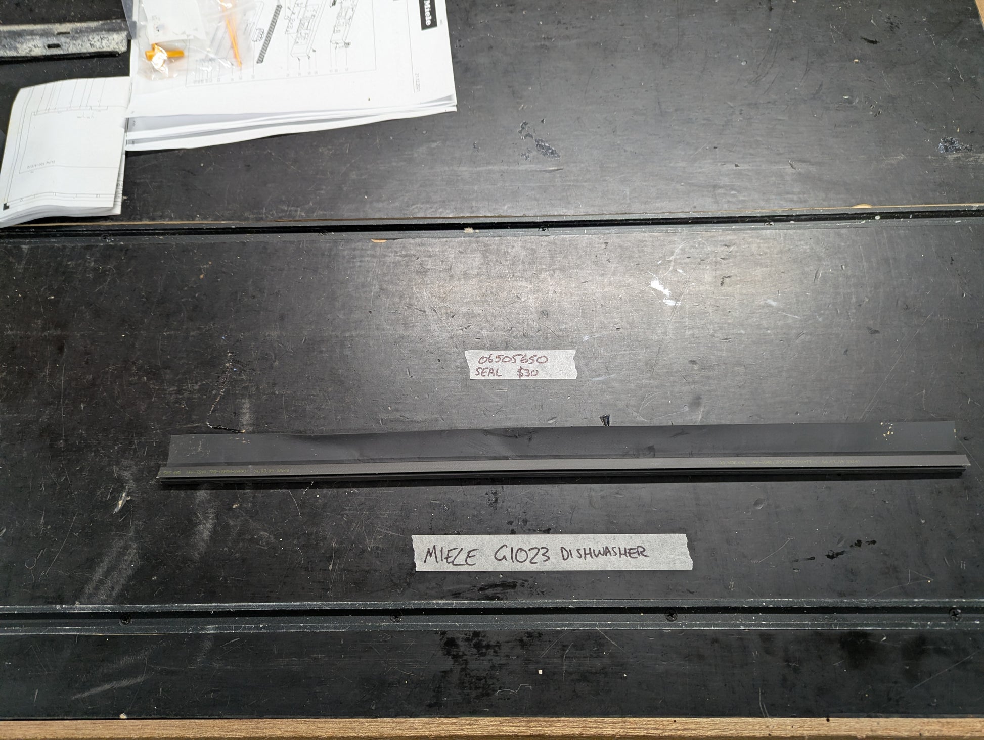 Miele G1023 dishwasher black rubber door seal on workbench with label