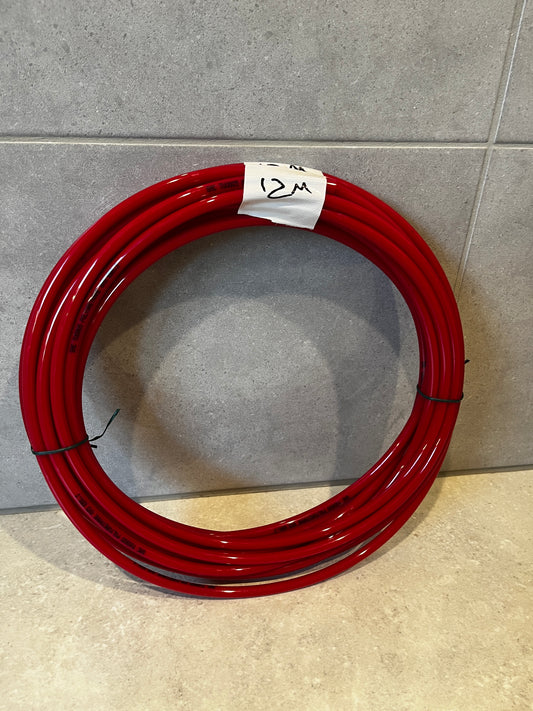 Coiled 12 meter red polyurethane tubing laid on floor with tape marked '12M'