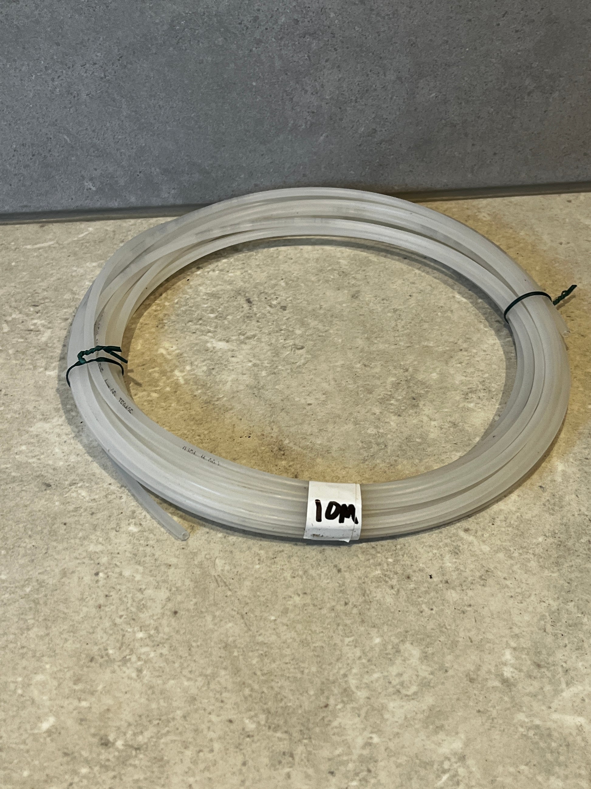 Coiled 10-meter polyethylene tubing on a stone surface