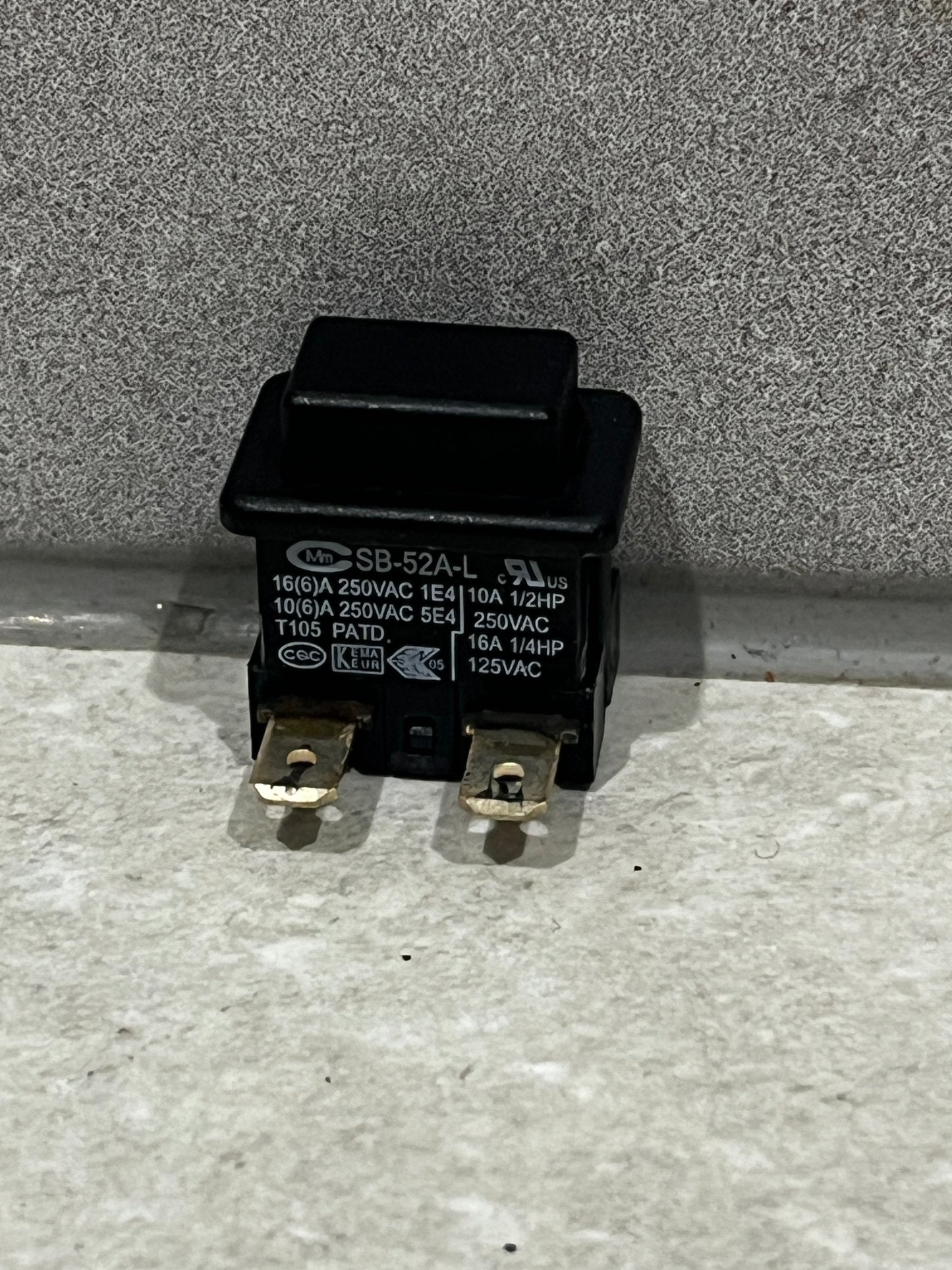 black SB-52A-L power switch with two metal terminals on gray surface