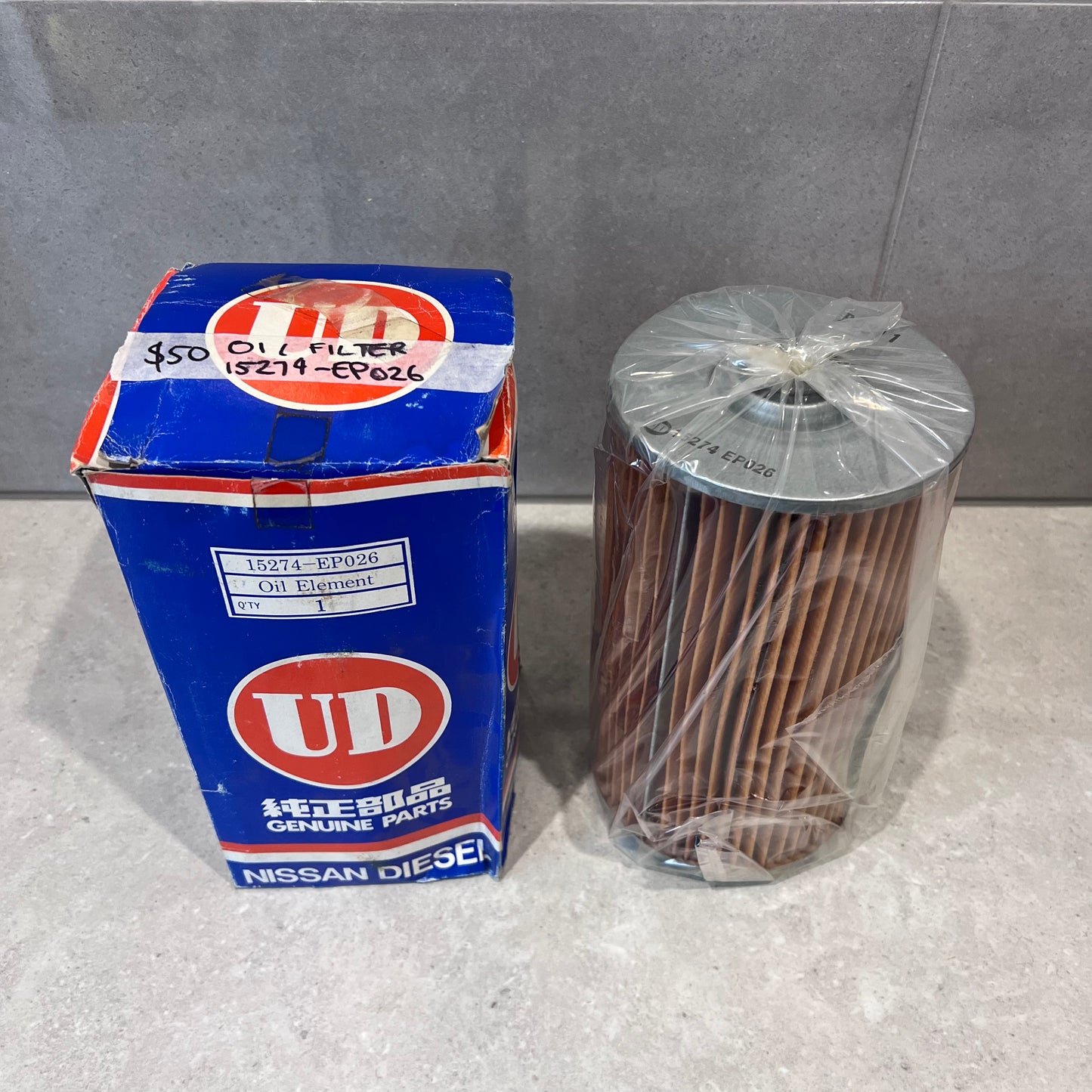 UD Nissan Diesel oil filter 15274-EP026 in box and plastic sleeve on counter