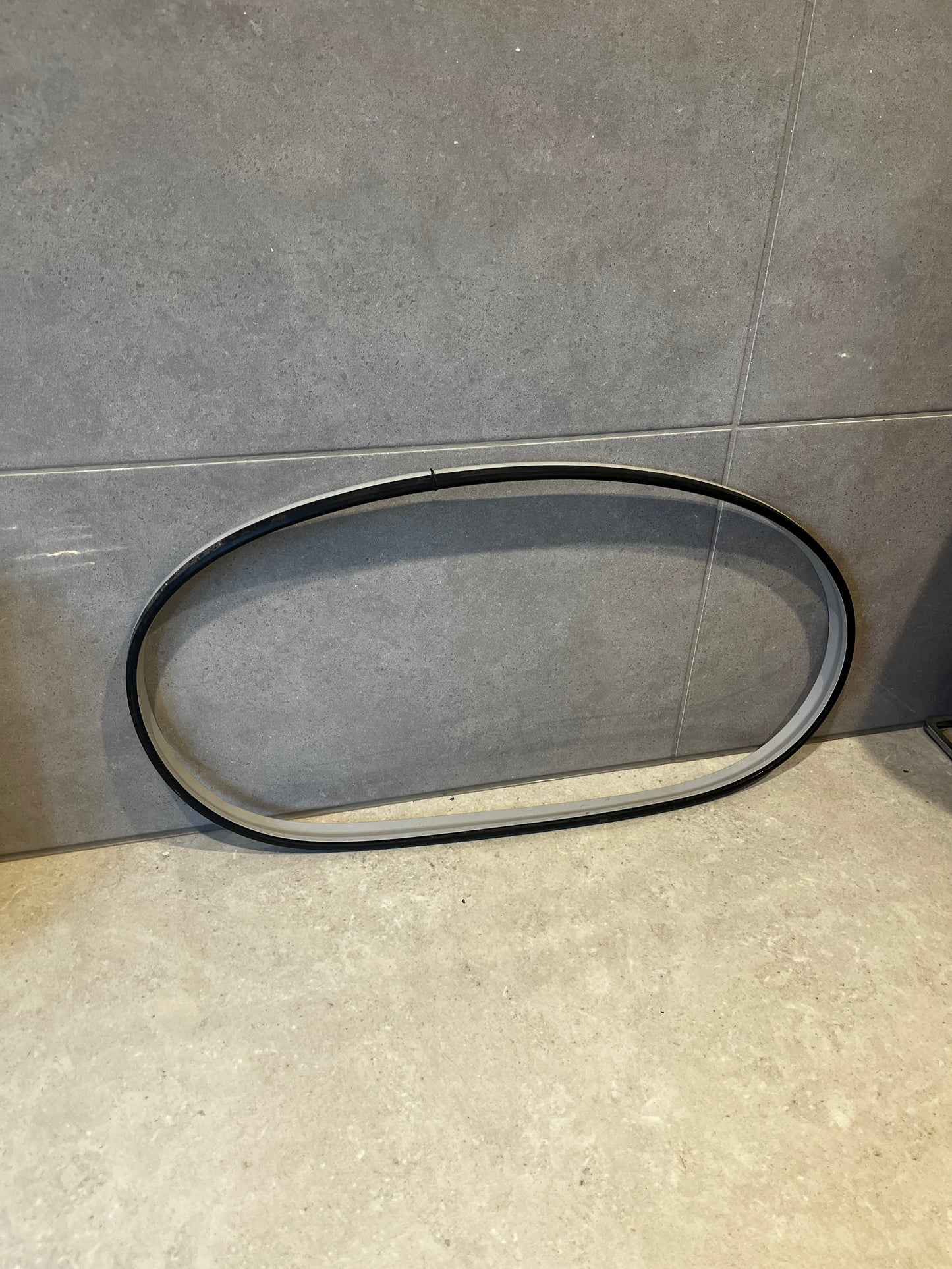 Flexible black washing machine door seal gasket on gray tile