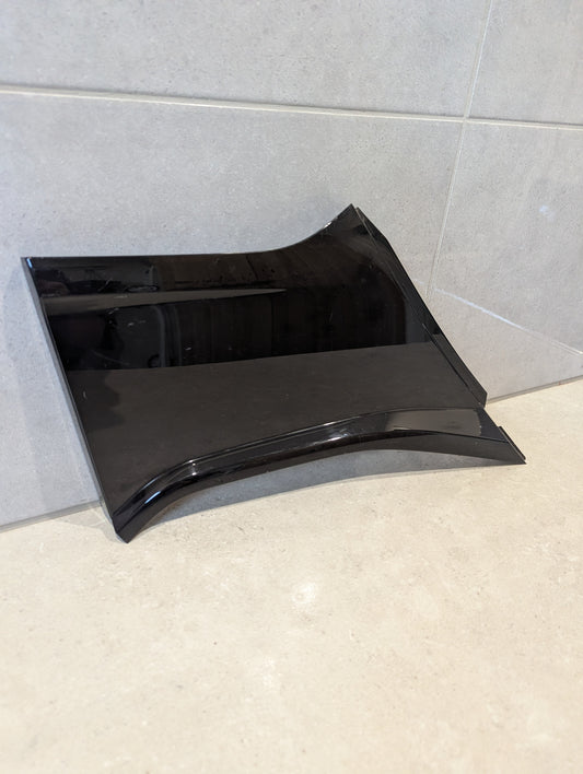 Glossy black automotive plastic side panel on tiled surface