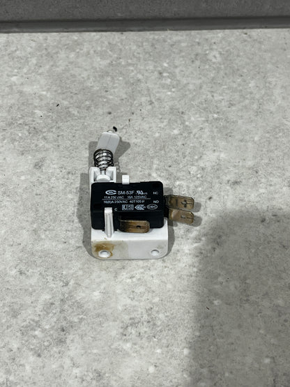Close-up of SM-53F micro switch with spring actuator mounted on white base showing metal terminals