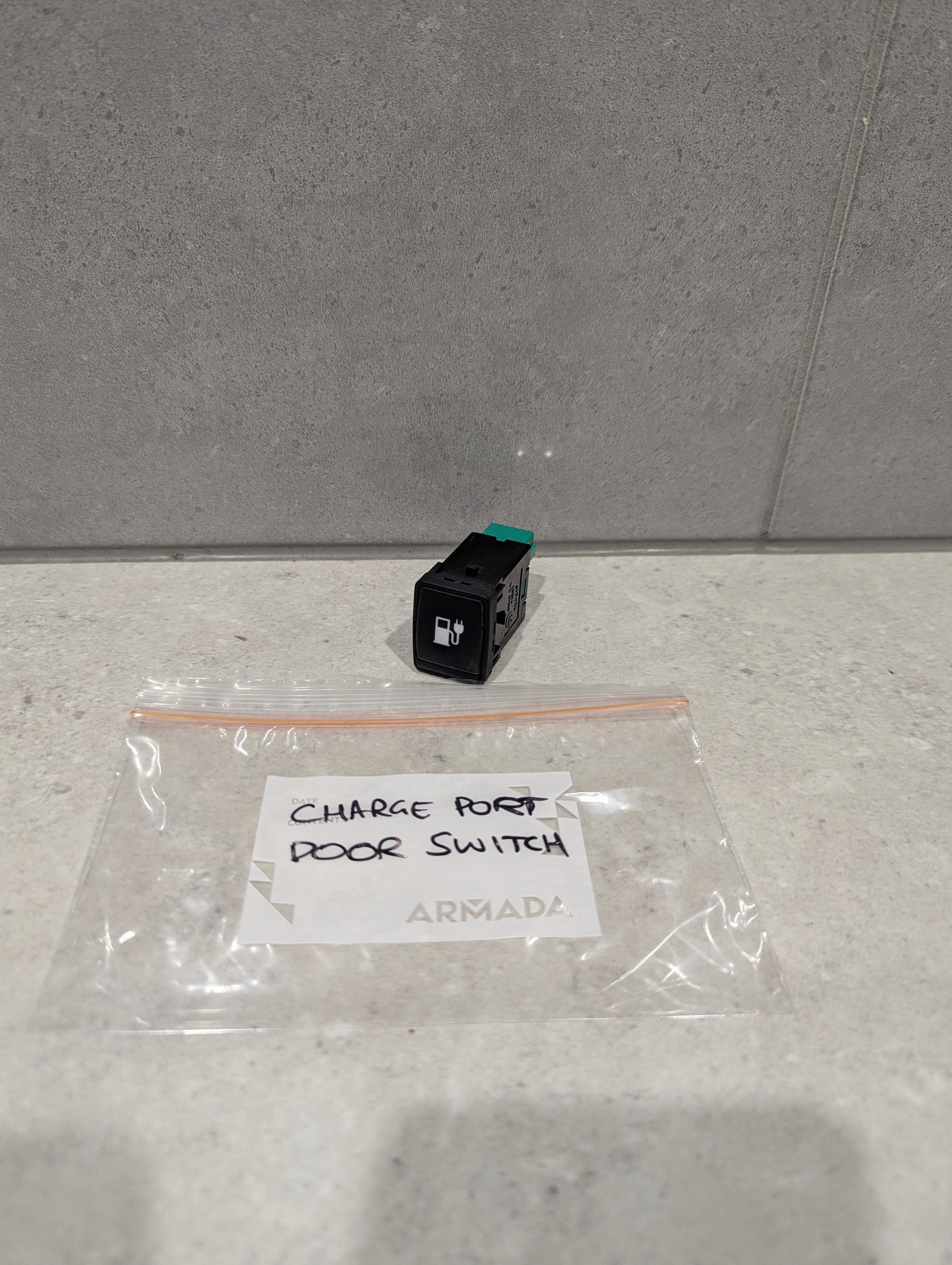 Charge port door switch replacement on countertop with labeled plastic bag