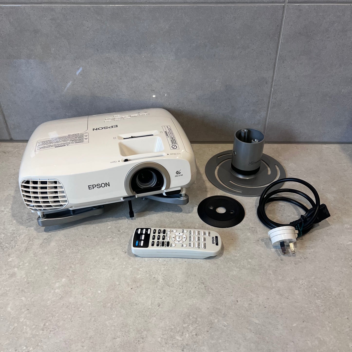 Epson EH-TW5200 projector with remote, power cable, and mounting accessories on countertop