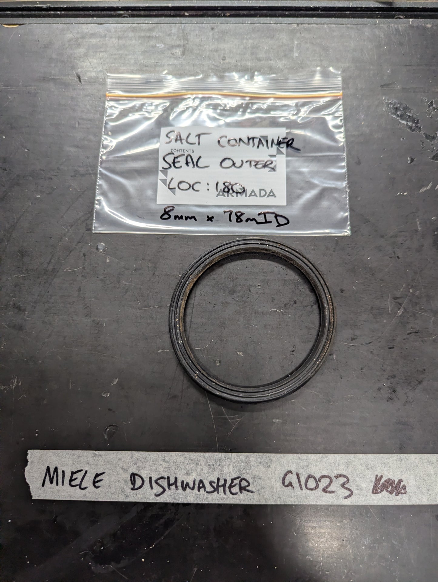 Black rubber outer seal for Miele G1023 dishwasher salt container, labeled bag and item