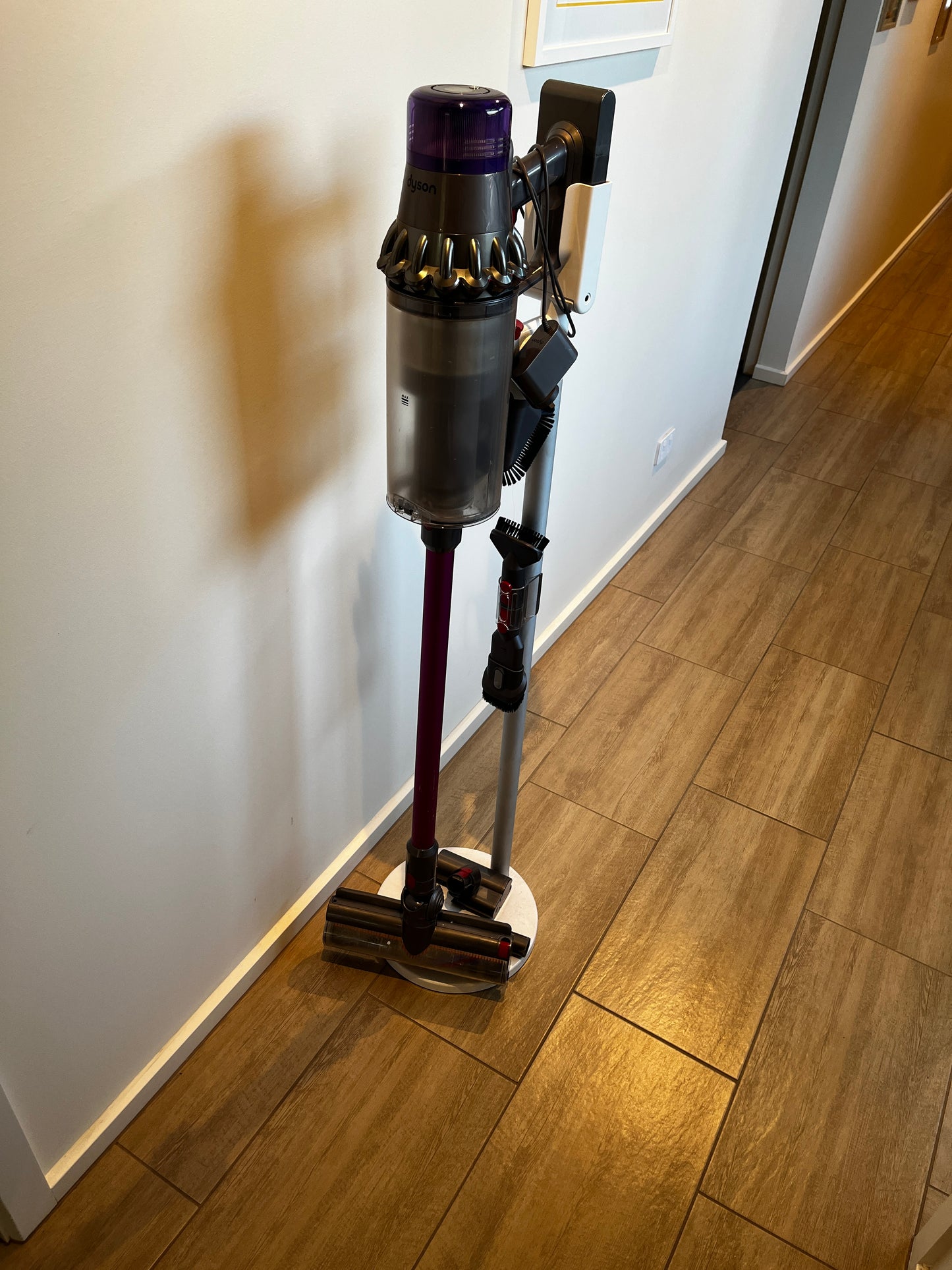 Dyson cordless stick vacuum cleaner on charging stand with floor head attachment