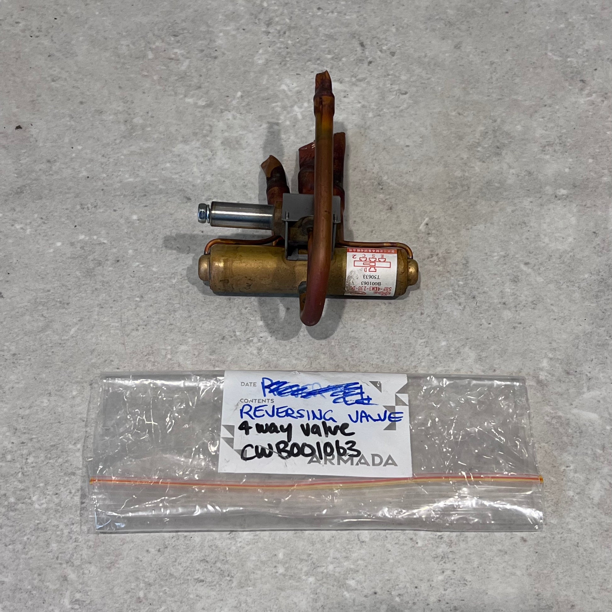 HVAC 4-way reversing valve with labeled storage bag on a light surface