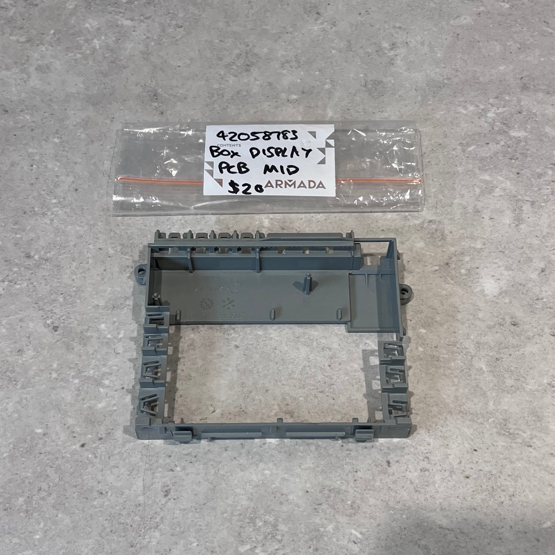 Gray plastic box display PCB mid frame with labeled bag on gray surface
