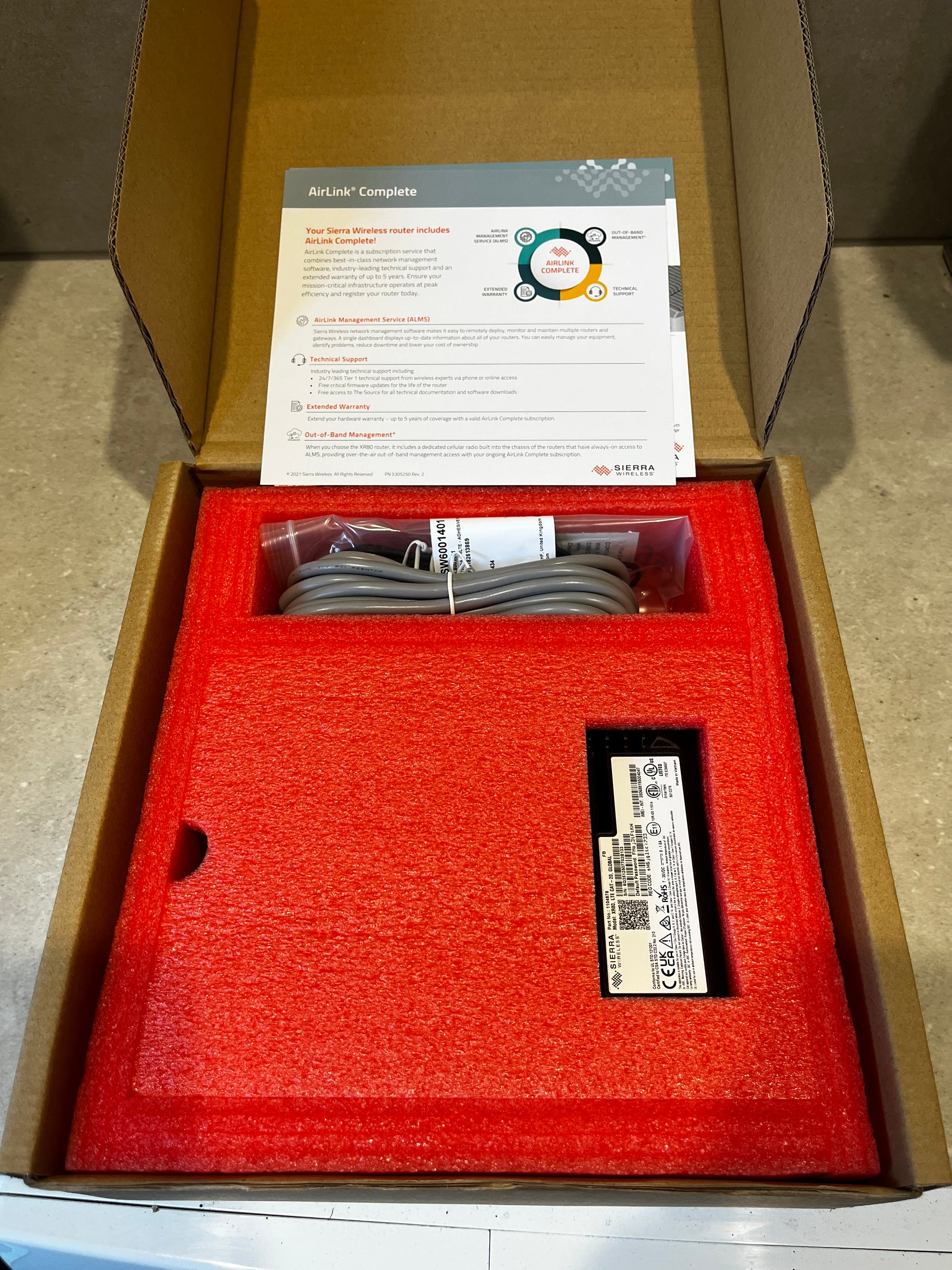 Open box showing AirLink Complete subscription service documentation and router in red protective foam