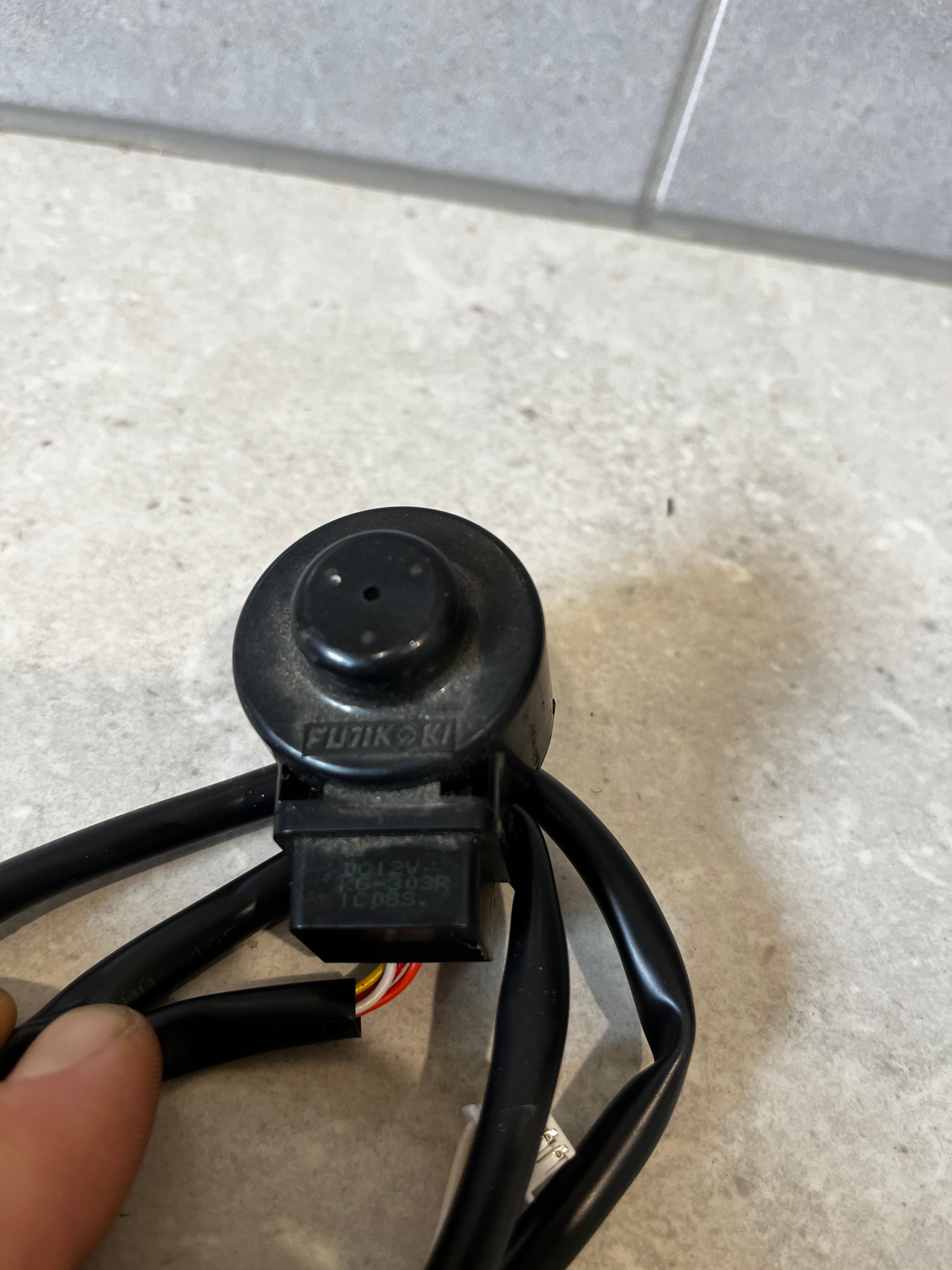 Close-up of Fujikoki solenoid valve and connector on gray background