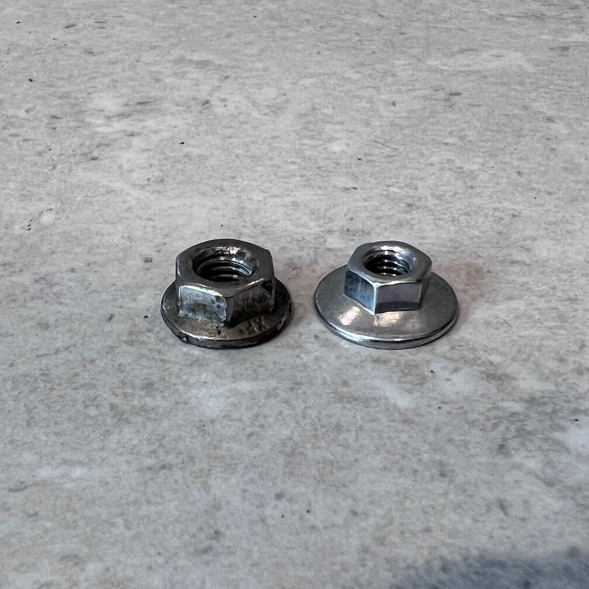 Two metal flange nuts side by side on a light surface