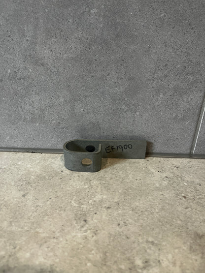 Steel mounting bracket with pre-drilled hole lying flat on a gray surface