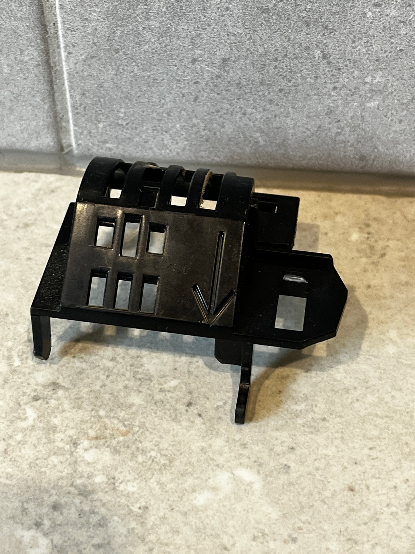 Angled top view of black mounting bracket showing arrow and cutout details