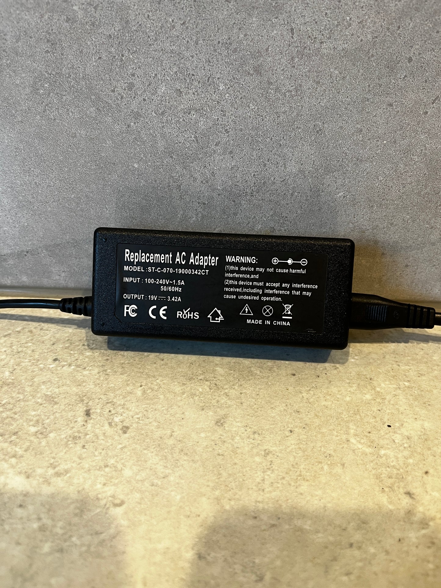 Close-up of Replacement AC Adapter label showing input and output specifications