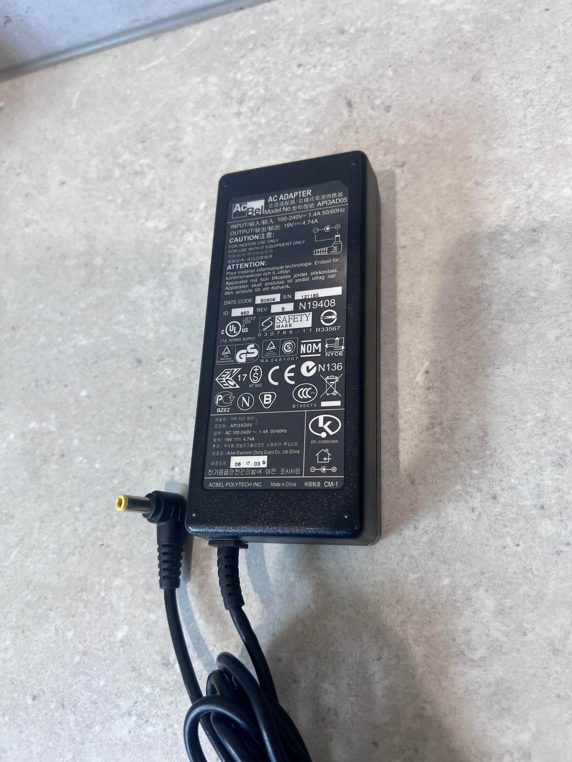Close-up view of AcBel AC adapter showing label and connector