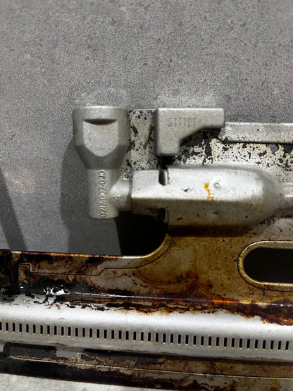 Close-up view of metal oven burner assembly showing gas outlet section and ignition electrode