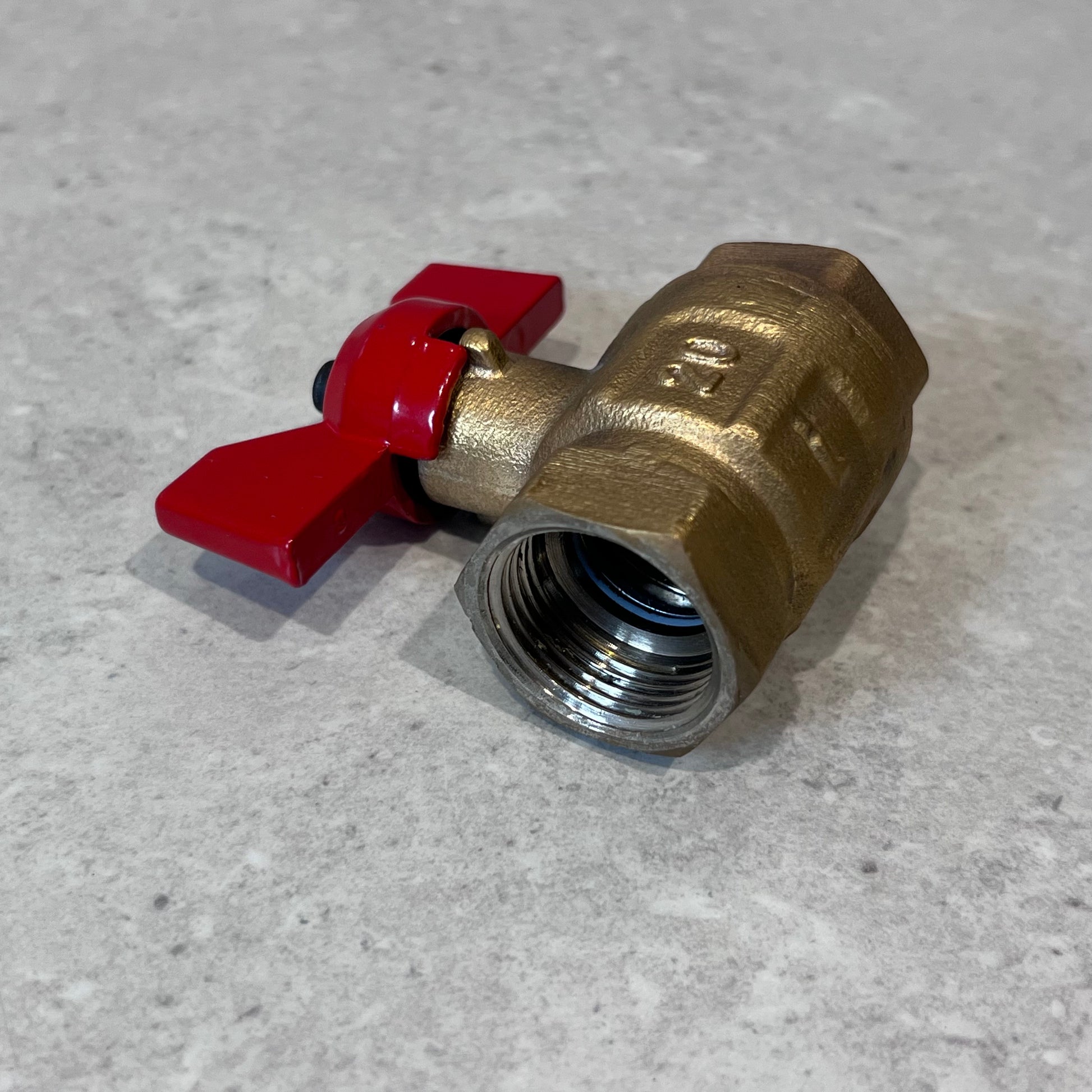 Close-up of brass ball valve with red butterfly handle showing threaded interior