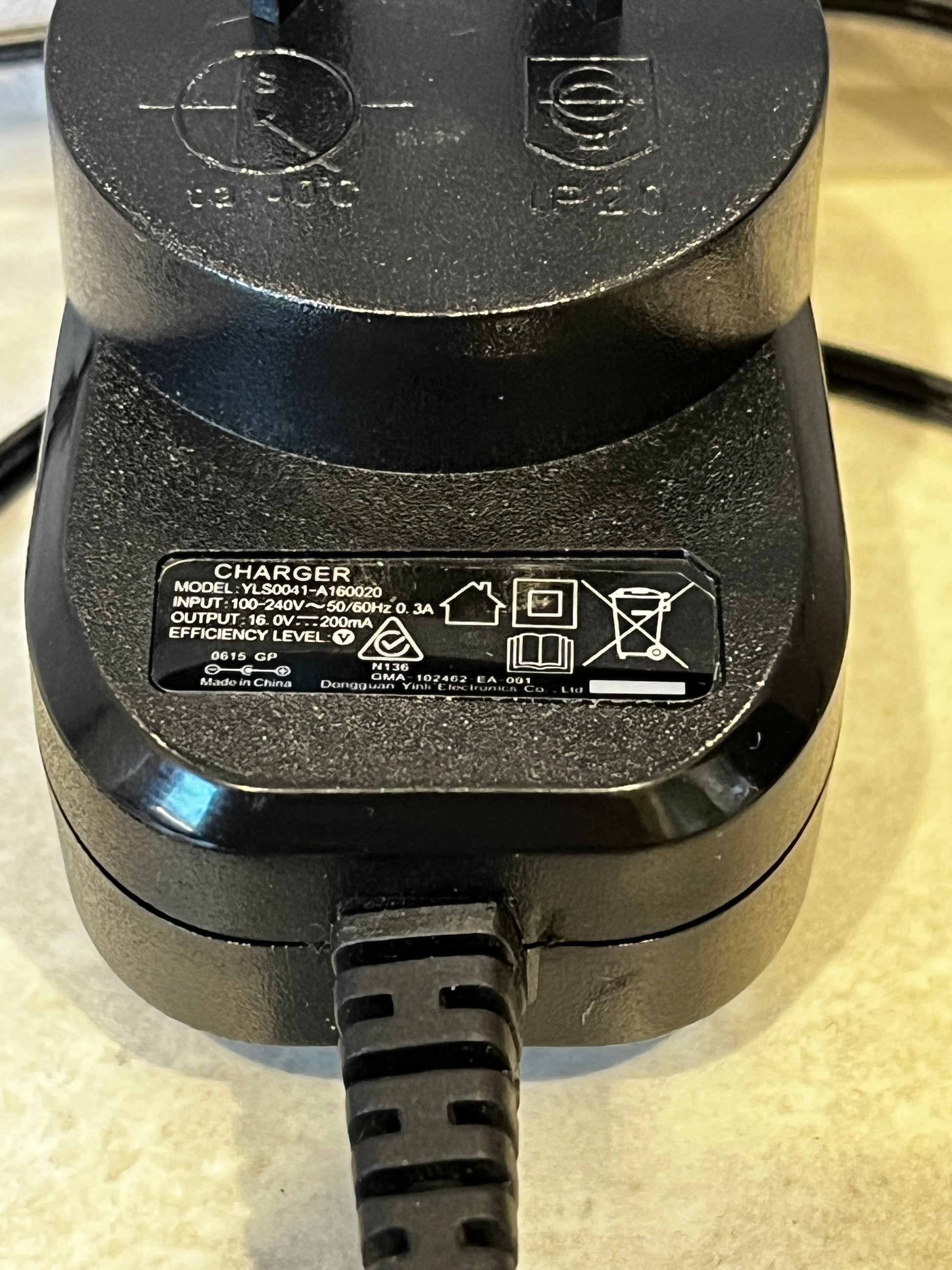 Black 16V 200mA power adapter with long cable on countertop