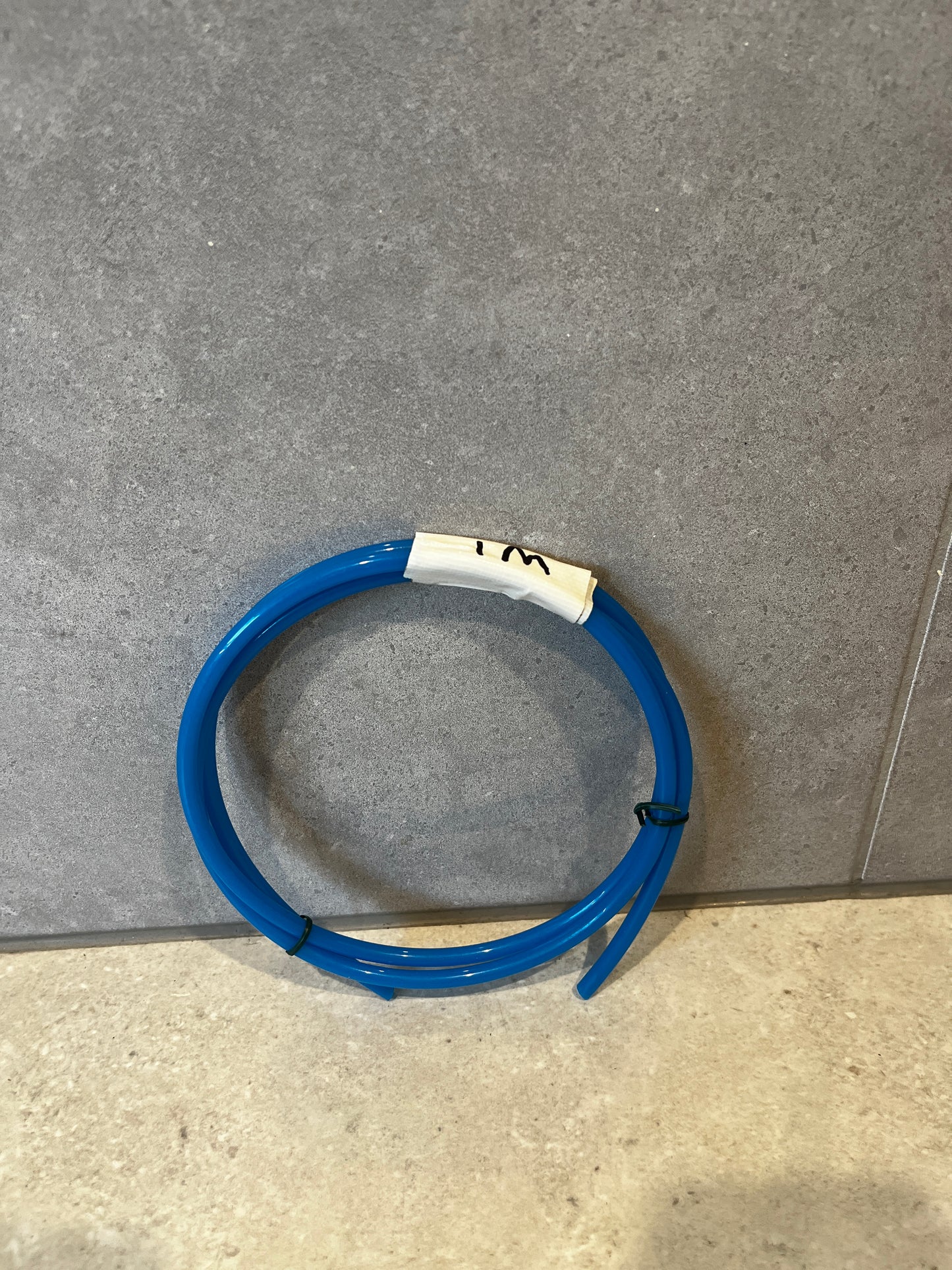 Overhead view of blue urethane tubing coiled against gray background